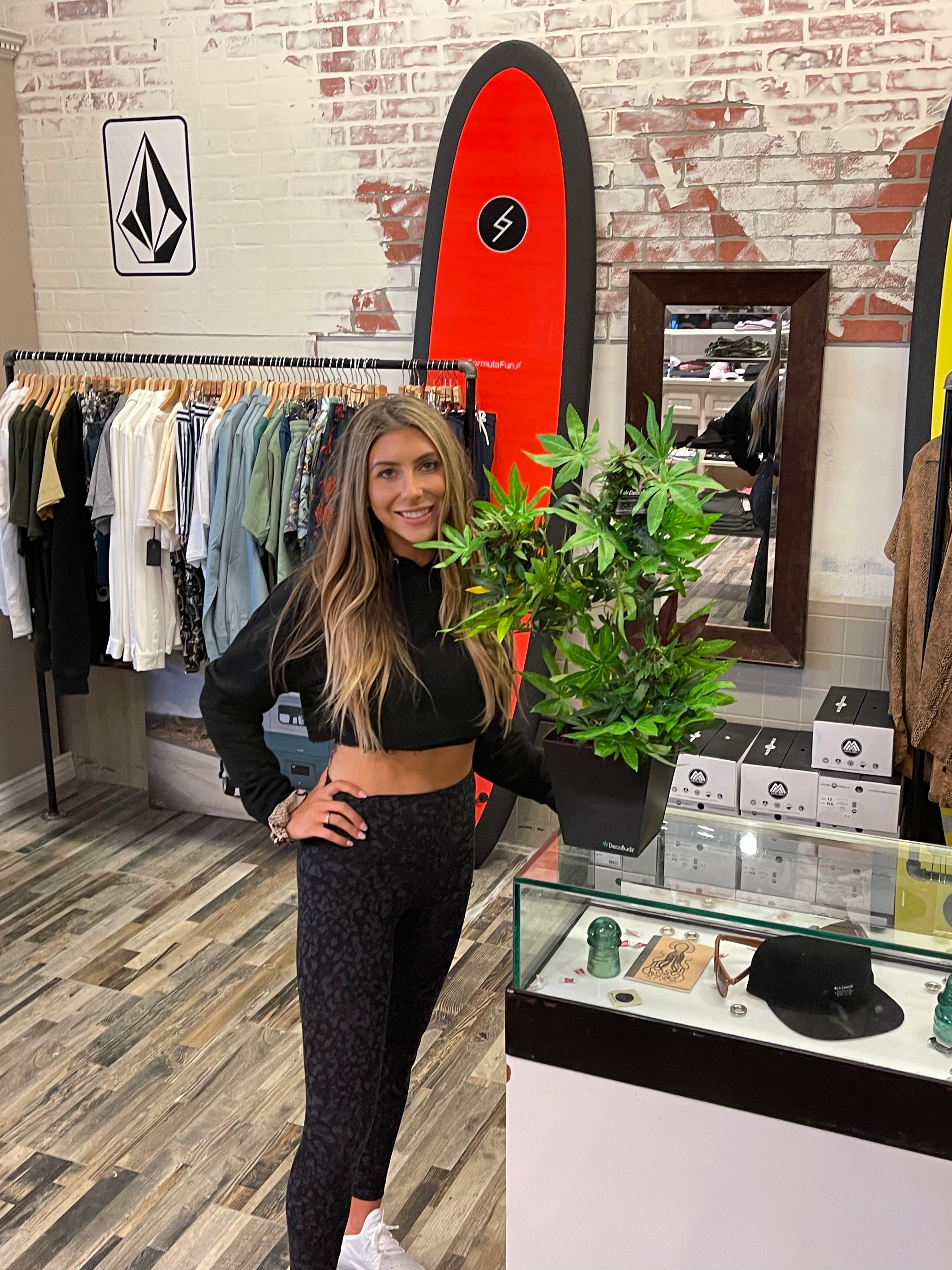 Cute girl in a CBD store holding a fine looking DecoBudz Fake pot plant 