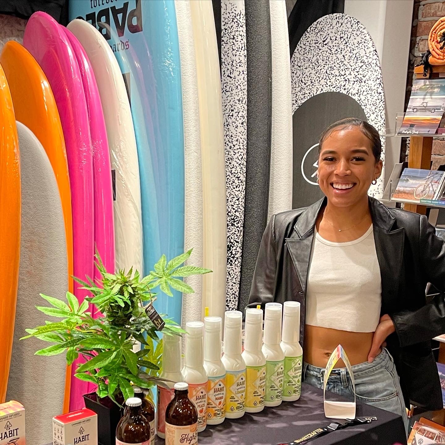 DecoBudz on display table showcasing canna  cbd products at a trade show surfboards in the background 